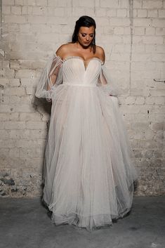 a woman in a white dress standing next to a brick wall with the caption instagram