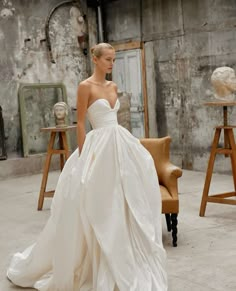 a woman in a white wedding dress standing next to a chair