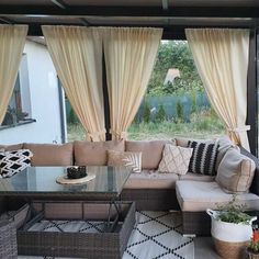 a living room filled with lots of furniture under a covered patio area next to a large window