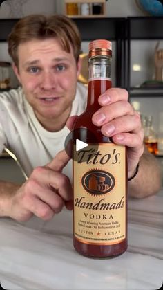 a man is holding up a bottle of hot sauce in front of him and posing for the camera