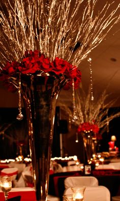 a vase filled with red roses sitting on top of a table covered in white linens