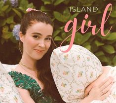 a woman holding a pillow with the words island girl written on it and flowers in the background