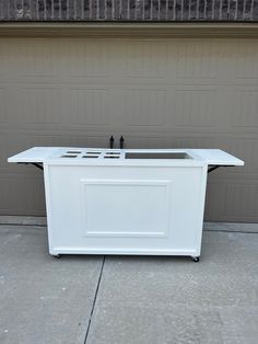 a white outdoor cooler sitting in front of a garage door with two black knobs on it