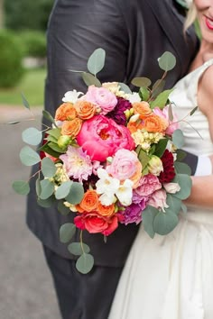 a bride and groom holding a bouquet of flowers