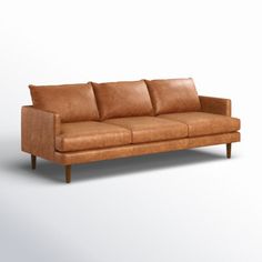 a brown leather couch sitting on top of a white floor next to a wooden frame