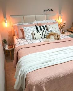 a cat laying on top of a bed next to pillows and lamps in a bedroom