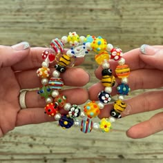 two hands holding bracelets with beads on them