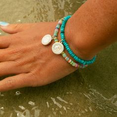 Get ready to ride the waves with our super fun Crystal Coast Beaded Bracelet! This vibrant piece is packed with aqua heishi shell beads that scream beach vibes and endless summer fun. The bright aqua beads remind you of clear blue waters and sunny skies, making it the perfect accessory to jazz up any look. - Wax coated nylon string, adjustable closure - Bracelet length adjustable from 2"-5" - 4mm aqua rondelle heishi beads - Features a small Silver / White St. Christopher Bohemian Letter Beads Beaded Bracelets For Beach, Bohemian Beaded Bracelets With Letter Beads For Beach, Bohemian Beach Beaded Bracelets With Letter Beads, Turquoise Strand Beaded Bracelets For Vacation, Turquoise Bracelets For Beach Season Festivals, Turquoise Beaded Strand Bracelets For Beach Season, Ocean-inspired Beaded Bracelets For Summer, Turquoise Beaded Strand Friendship Bracelet, Turquoise Friendship Bracelets With Colorful Beads For Summer