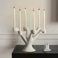 a group of white candles sitting on top of a table next to a figurine