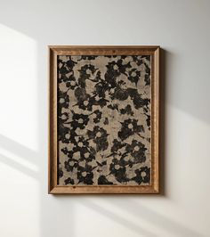 an abstract painting hanging on the wall in a room with white walls and wooden frame