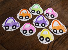 six paper heart shaped stickers with cars painted on them, sitting on a wooden table