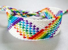 a close up of a colorful bracelet on a white surface with a knot at the end