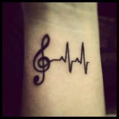 a tattoo with music notes and a treble on the side of the wrist,