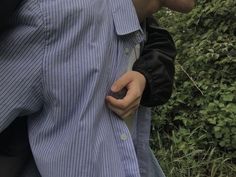 a man wearing a blue shirt and black gloves is holding his cell phone in his pocket