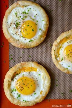 three fried eggs are in the middle of two small pies on a baking sheet