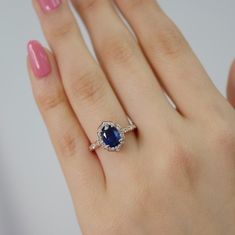 a woman's hand with a diamond and blue sapphire ring on her left hand