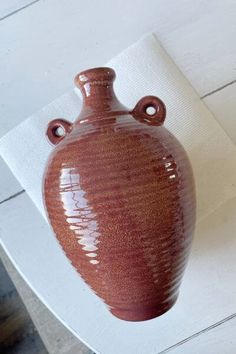 a brown vase sitting on top of a white table