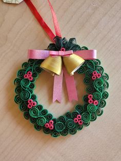 an ornament made out of paper and ribbon with bells on the top, sitting on a table