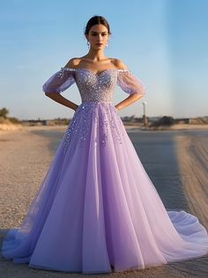 a woman in a purple dress standing on the beach with her hands on her hips