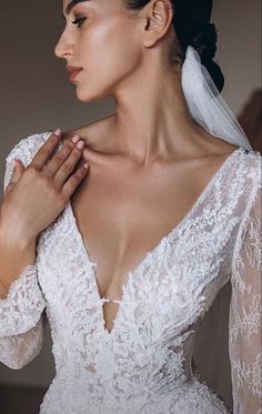 a woman wearing a white wedding dress with long sleeves and a veil on her head