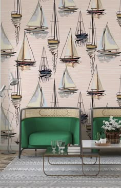 two green chairs sitting next to each other in front of a wall with sailboats on it