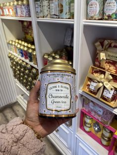 a person holding up a jar of food in front of a shelf full of goods