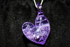 SUMMARY This lovely glass heart pendant has been infused with cremation ash from your loved one, making it a lovely way to keep them close to your heart. This piece works well as a solo pendant or as part of a larger piece. This piece is offered in several color variants, pictured is purple. Exact shape and color will vary from piece to piece. DETAILS We ask for approximately 1/4th a teaspoon of cremains. The pendant measures approximately 7/8" in diameter, not including bail, and weighs approxi Glass Heart Necklace, Artful Ashes, 7 Jewelry, Translucent Glass, Memorial Necklace, Glass Heart, Close To My Heart, Clothes Jewelry, Shades Of Purple