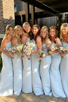 a group of women standing next to each other holding bouquets in front of a building