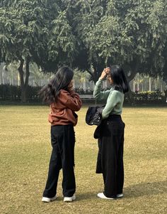 two women standing in the grass taking pictures