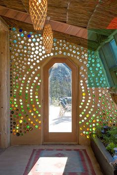 a room with a door and some lights hanging from it's ceiling, surrounded by plants