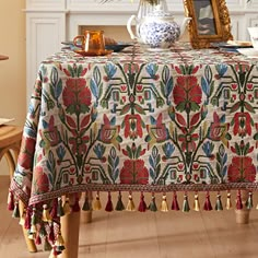 the table cloth is decorated with colorful flowers and tassels on it's legs