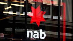 a canadian maple leaf is reflected in the glass windows of a nab storefront