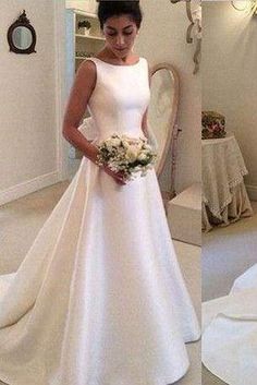 a woman in a white wedding dress standing next to a mirror and holding a bouquet