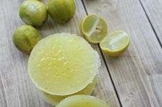 three lemons and one lime on a wooden table