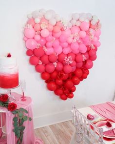 a heart shaped balloon filled with pink and white balloons on a wall above a table