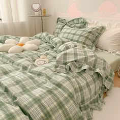 an unmade bed with green plaid sheets and pillows