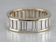 This ring has a wonderful tapered shape, domed profile, and an endless row of channel set diamonds! The diamonds are all baguette cuts, which gives the ring a unique sparkle, luxurious without being ostentatious. Metal: 14K Yellow Gold Gem: 30 Diamonds totaling 5.10 Carats, VVS1 in Clarity, G in Color Width of Band: 6.3 mm Height off Finger: 2.9 mm Ring Size: 7 Marks: "14K" Stamped on the inside band Baguette Diamond Band, White Gold Diamond Band, Vintage Diamond Wedding Bands, Platinum Wedding Band, Gold Diamond Band, Diamond Eternity Band, Diamond Anniversary Rings, Engagement Ring Cuts, Diamond Anniversary