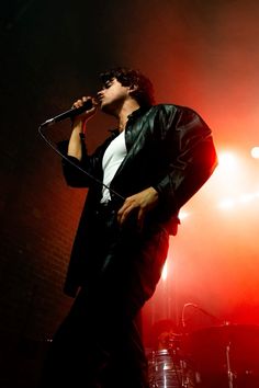 a man standing in front of a microphone on top of a red and black stage