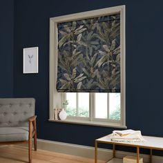 a living room with blue walls and a window that has a leaf pattern on it