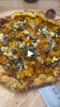 a pizza sitting on top of a wooden cutting board with a knife in front of it