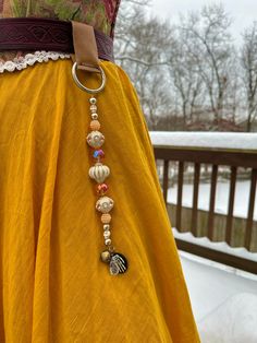 a woman wearing a yellow dress with a brown belt and beaded necklace on her waist