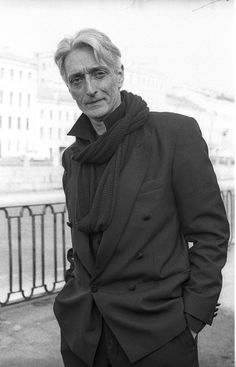 black and white photograph of an older man in a suit standing on the sidewalk with his hands in his pockets