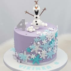 a purple and blue frosted birthday cake with snowflakes on it, the number four