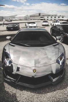 the front end of a silver sports car parked in a parking lot next to other cars