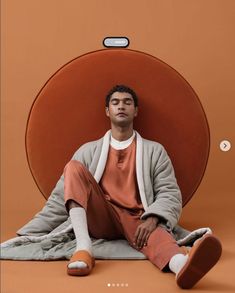 a man sitting on the ground with his feet up in front of an orange circle