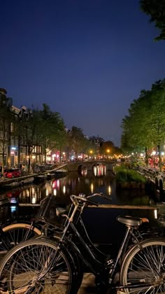 two bikes parked next to each other on the side of a river at night time