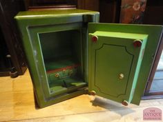 an open green cabinet sitting on top of a wooden floor