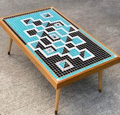 a coffee table with blue and black mosaic tiles on the top, sitting on carpeted area