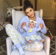 a woman sitting in a chair holding a baby wearing winnie the pooh pajama