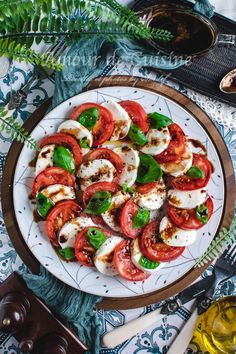 a white plate topped with sliced tomatoes and mozzarella on top of a table